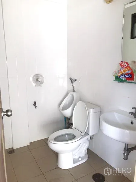 Townhouse for rent in Khlong Toei, Bangkok - Clean bathroom with toilet, urinal, sink and mirror on white tiles.