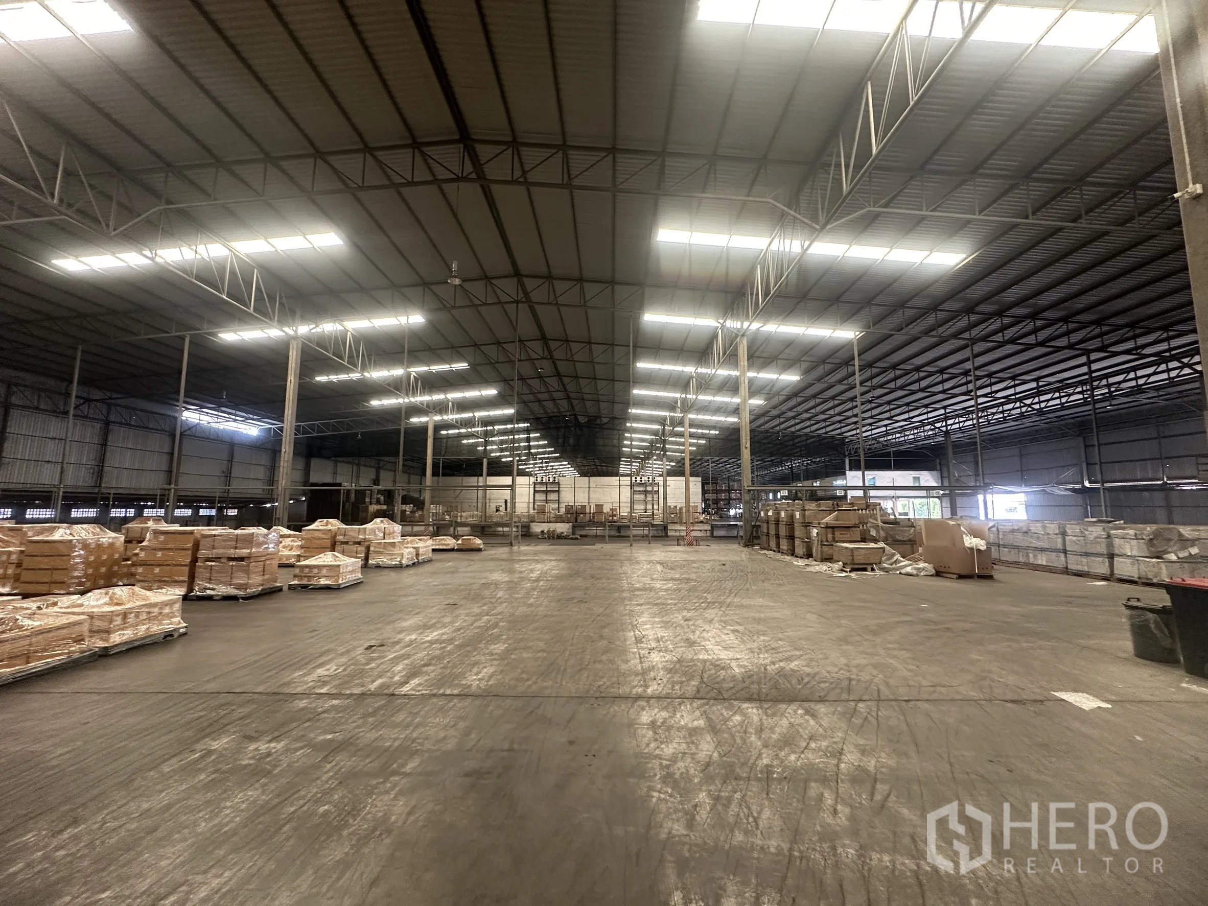Warehouse for rent in Bang Pa-in, Phra Nakhon Si Ayutthaya - Central view of the warehouse showing bright lighting, pallets, and an internal office area.
