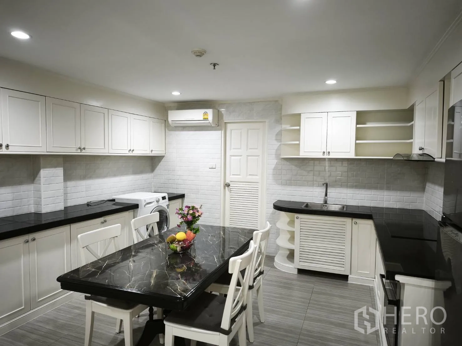คอนโด for rent in Watthana, Bangkok - ครัวสีขาวกว้าง เคาน์เตอร์หินสีดำ โต๊ะทานอาหาร และเครื่องซักผ้าพร้อมตู้เก็บของมากมาย