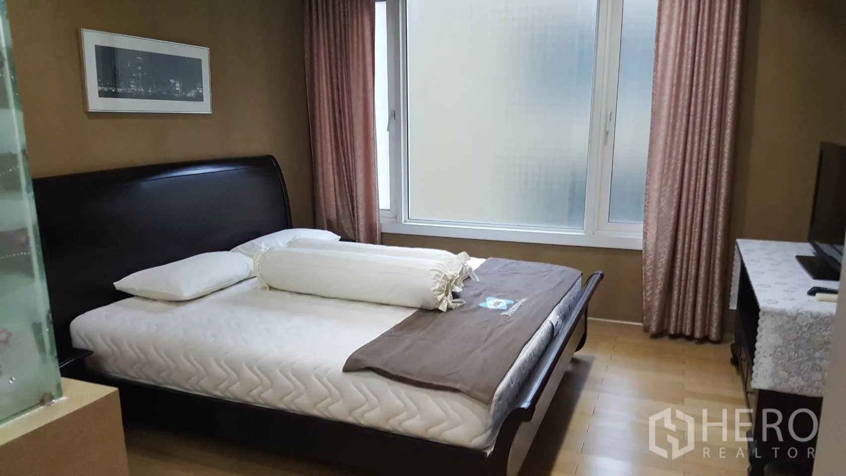 Condominium for rent in Khlong Toei, Bangkok - Bright bedroom with large window, pink curtains and dark wood bed frame.