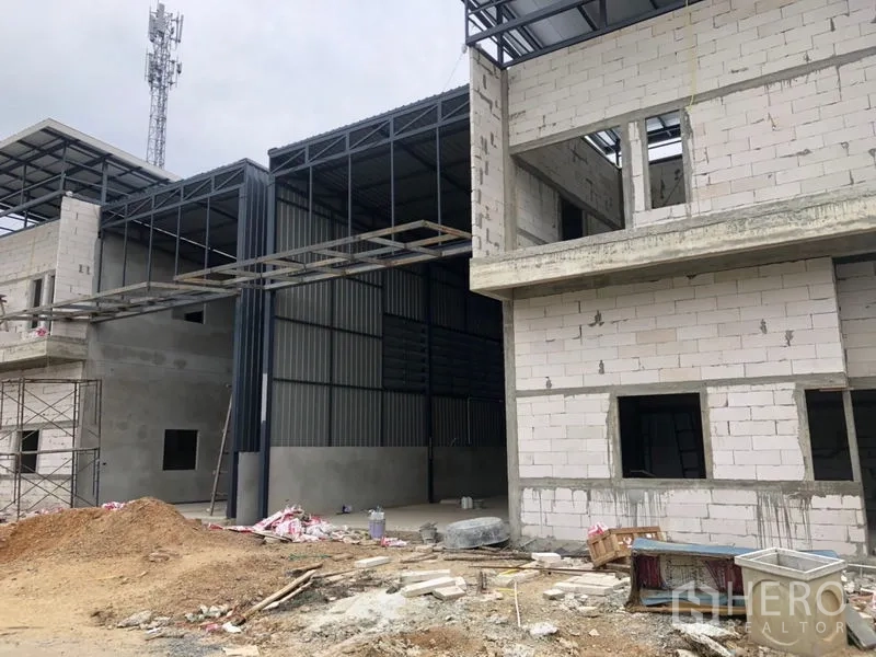 Warehouse for rent in Lam Luk Ka, Pathum Thani - Wide view of the warehouse complex along a local road with power lines.