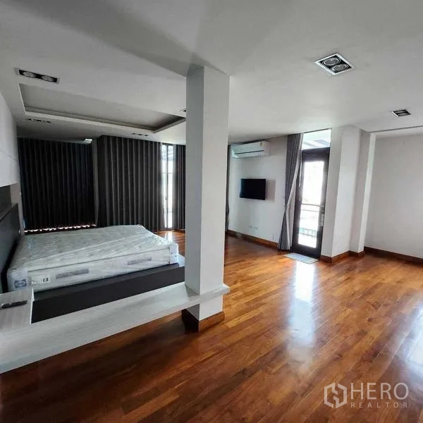 独立式住宅 出售在Phra Khanong, Bangkok - 转角卧室，立柱、阳台门、电视与暖色木地板