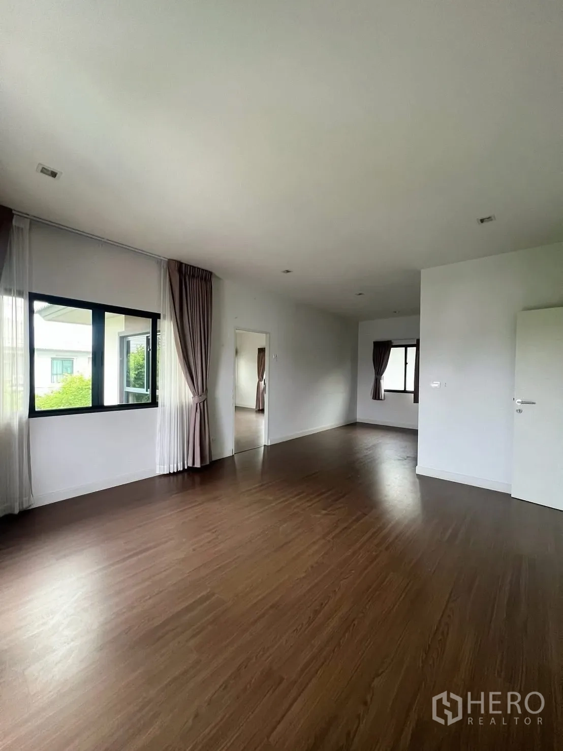 Detached House for rent in Bang Phli, Samut Prakan - Spacious upper-floor room with wood-look flooring and curtained windows.