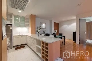 公寓 出租在Bang Rak, Bangkok - U形厨房，白色台面、岛台吧台与充足收纳。