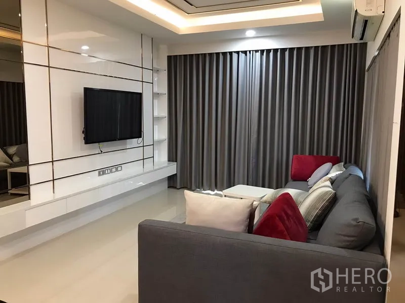 Detached House for rent in Bang Phli, Samut Prakan - Bright living room with built-in TV wall, gray blackout curtains, recessed lighting and L-shaped sofa.