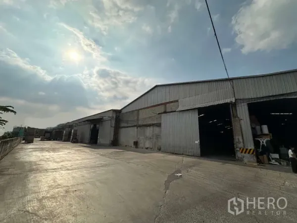 Warehouse for rent in Mueang Pathum Thani, Pathum Thani - Front facade of industrial warehouse with large sliding doors and truck access.