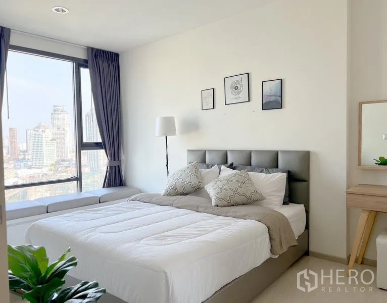 Condominium for rent or sale in Khlong Toei, Bangkok - Bedroom with large windows, upholstered bed, desk and expansive city views.