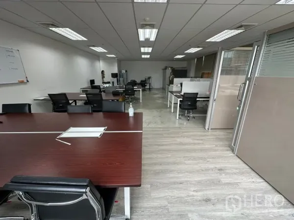 Office Space for rent in Khlong Toei, Bangkok - Open-plan office with multiple workstations, glass partitions and wood-look floors under bright ceiling lights.
