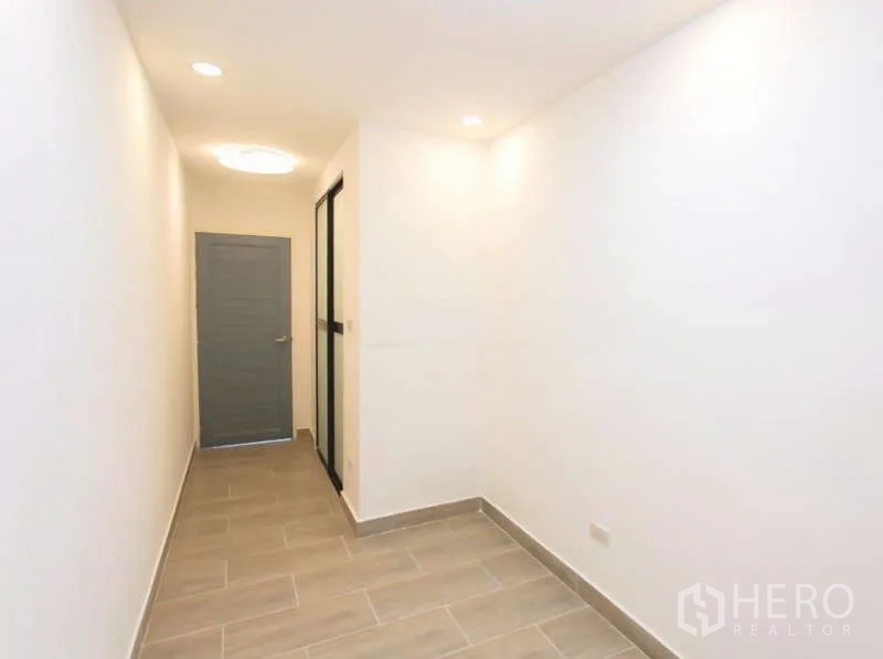 Detached House for sale in Wang Thonglang, Bangkok - Clean hallway with tiled floor, recessed lights, a sliding glass partition and grey door.