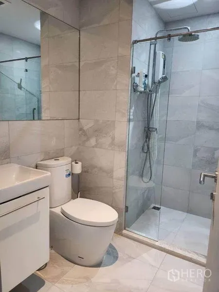 公寓 出租在Watthana, Bangkok - 现代卫浴，仿大理石瓷砖，玻璃淋浴房、顶喷花洒及洗手台与坐便器。
