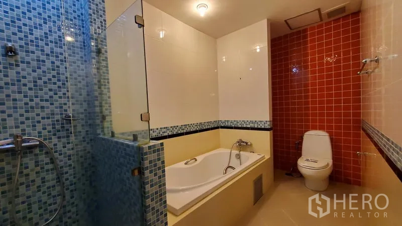 Condominium for rent in Khlong Toei, Bangkok - Bathroom with soaking tub, separate glass shower and blue mosaic tiles.