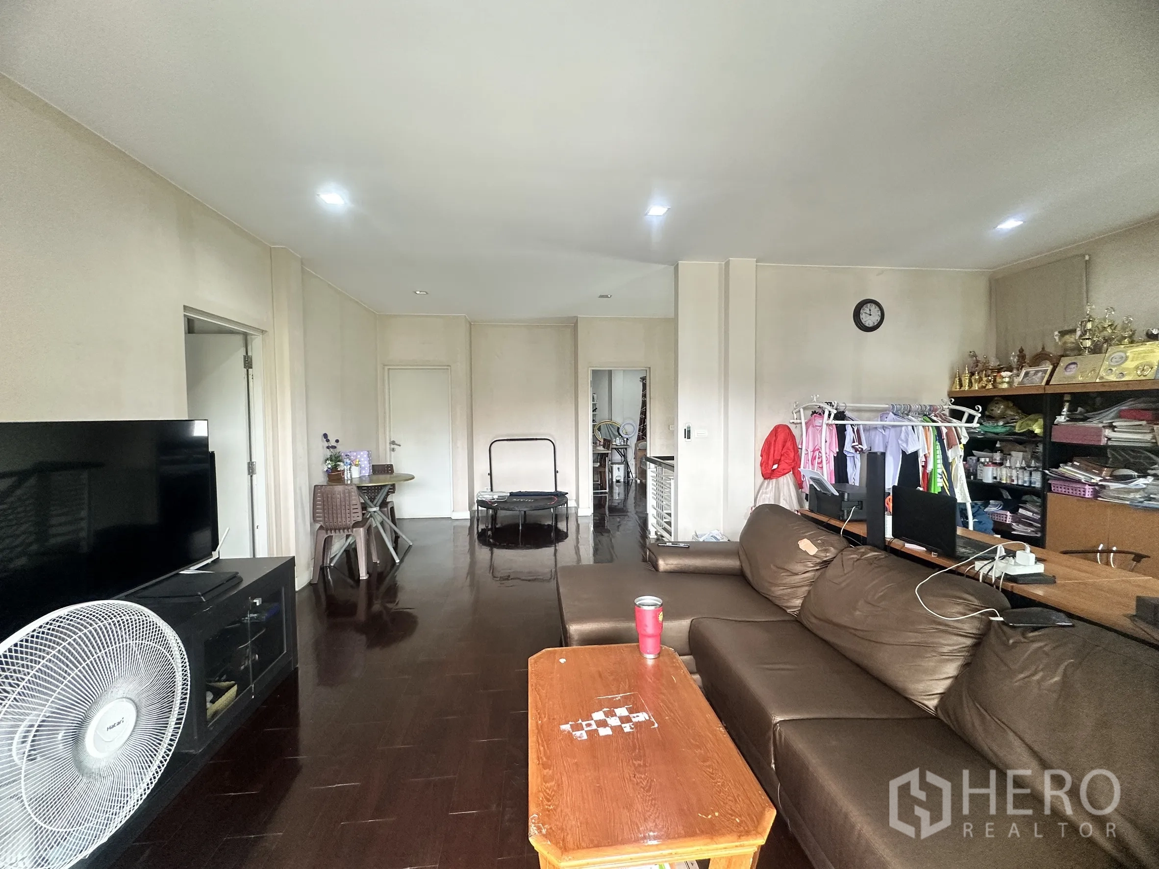 独栋房屋 for sale in Pak Kret, Nonthaburi - 客厅配棕色皮沙发、电视柜与木地板。