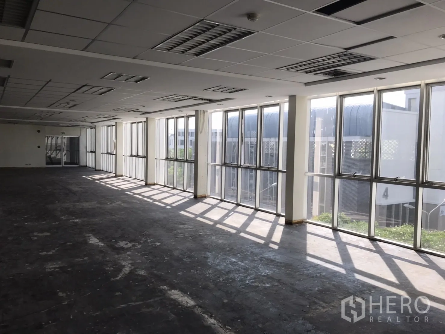 办公空间 出租在Khlong Toei, Bangkok - 室内明亮，连续落地窗与城市景观，靠近 BTS Phra Khanong。