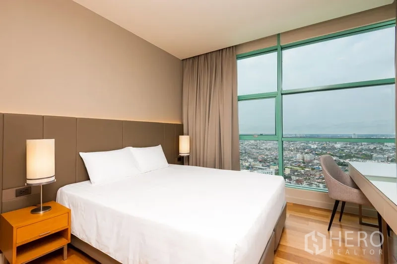Condominium for rent in Bang Kho Laem, Bangkok - Bedroom with king bed and floor‑to‑ceiling windows overlooking the city skyline.