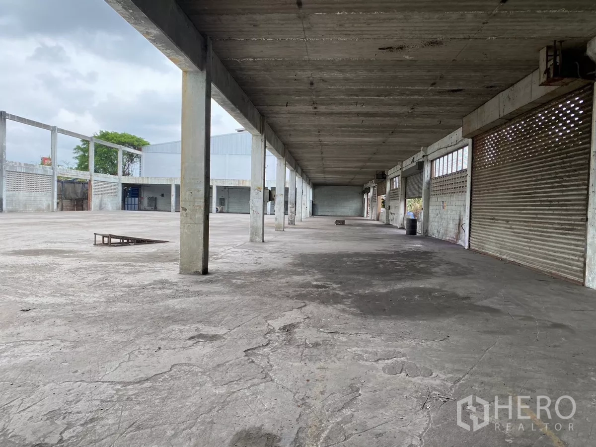 Factory for sale in Bang Phli, Samut Prakan - Long covered corridor with roller shutters facing the yard.