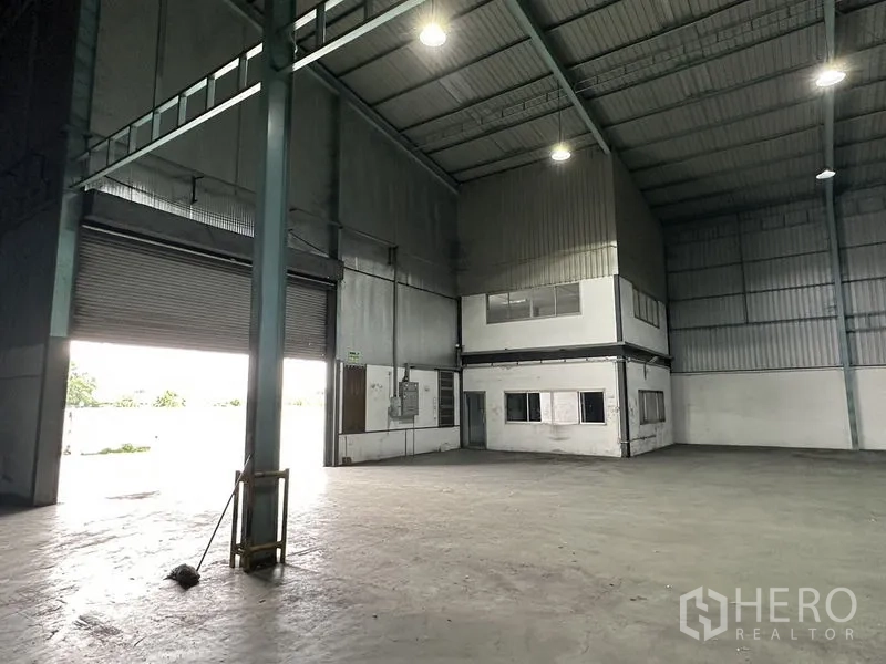 Warehouse for rent in Mueang Samut Prakan, Samut Prakan - Loading zone with large roller shutter and an elevated enclosed office box inside the warehouse.