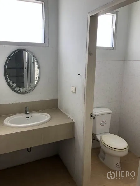Factory for rent in Pathum Thani - Clean restroom with separate toilet cubicle, sink and mirror inside the factory.