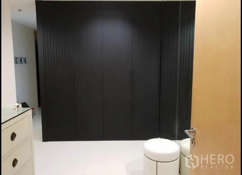 Condominium for rent in Sathon, Bangkok - Spacious dressing area with large black built-in wardrobes and a round ottoman.