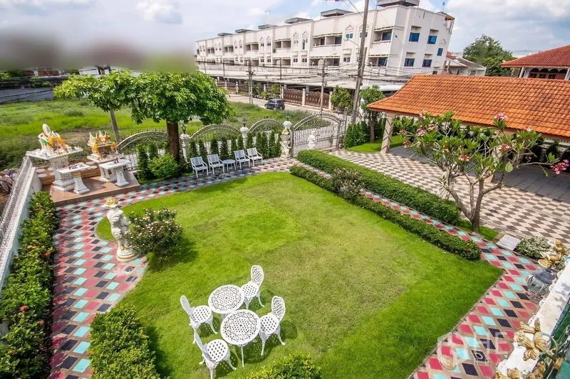Detached House for rent or sale in Bang Khen, Bangkok - Bird’s‑eye view of a large rectangular lawn bordered by colorful tiles, patio seating, and a gated entrance with carport.