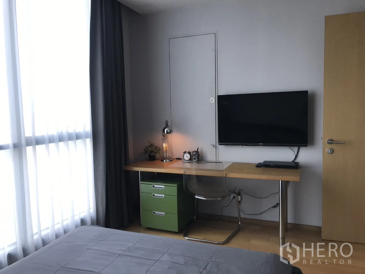 Condominium for rent in Watthana, Bangkok - Bedroom workspace with long wooden desk, drawers and a wall-mounted TV.