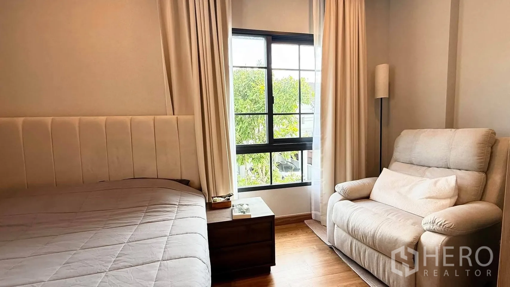 บ้านเดี่ยว for rent in Bang Phli, Samut Prakan - มุมห้องนอนสว่างด้วยหน้าต่างบานใหญ่ เก้าอี้เอนกาย โต๊ะข้าง และผ้าม่าน