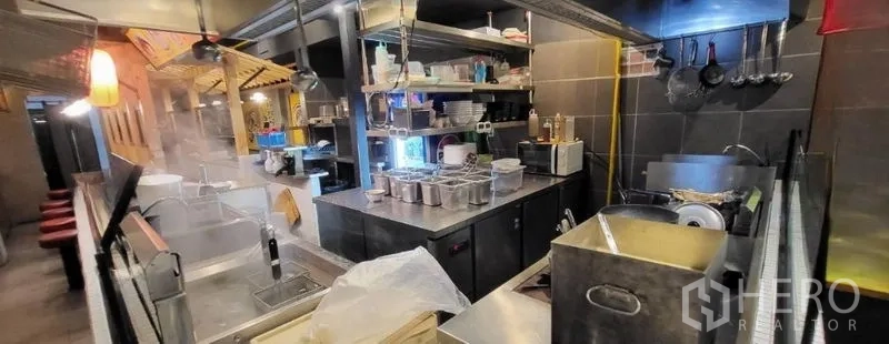 Shophouse for rent in Khlong Toei, Bangkok - Commercial kitchen with stainless equipment, sinks and storage shelves.