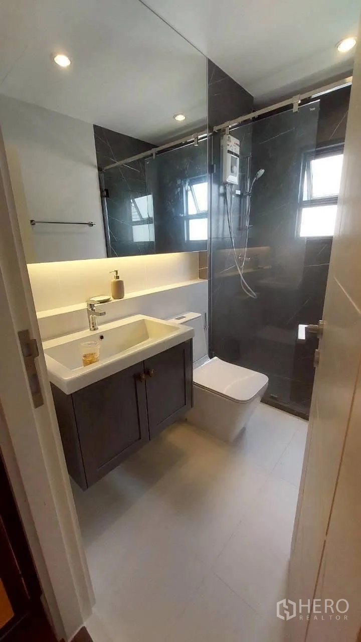 Detached House for rent in Bang Phli, Samut Prakan - Modern bathroom with glass shower, vanity, and warm lighting.