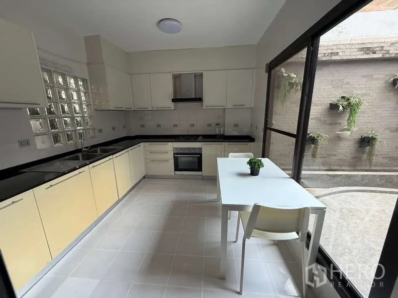 Townhouse for rent in Khlong Toei, Bangkok - Separate kitchen with ample cabinets, built-in oven and courtyard view.