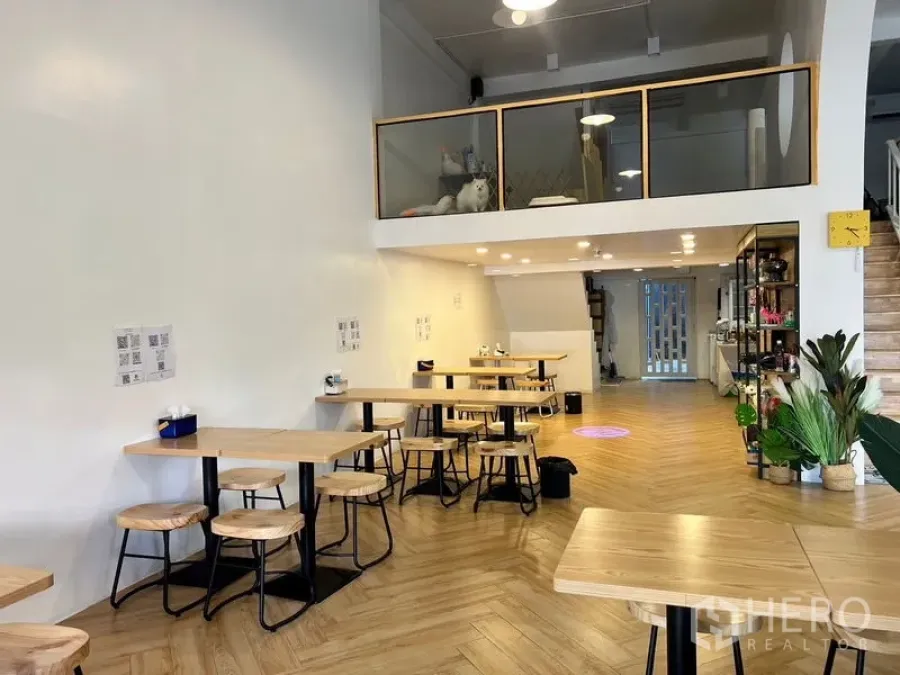 Shophouse for rent in Phra Khanong, Bangkok - Bright shophouse dining area with high ceiling, mezzanine and herringbone wood floors.