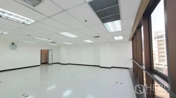 办公空间 出租在Watthana, Bangkok - 开放办公空间，长排窗户、荧光灯与空调出风口，旁侧有通往内室的门。