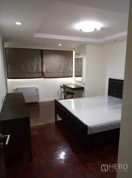 Condominium for rent in Watthana, Bangkok - Bright bedroom with desk, blackout blinds, and parquet flooring.