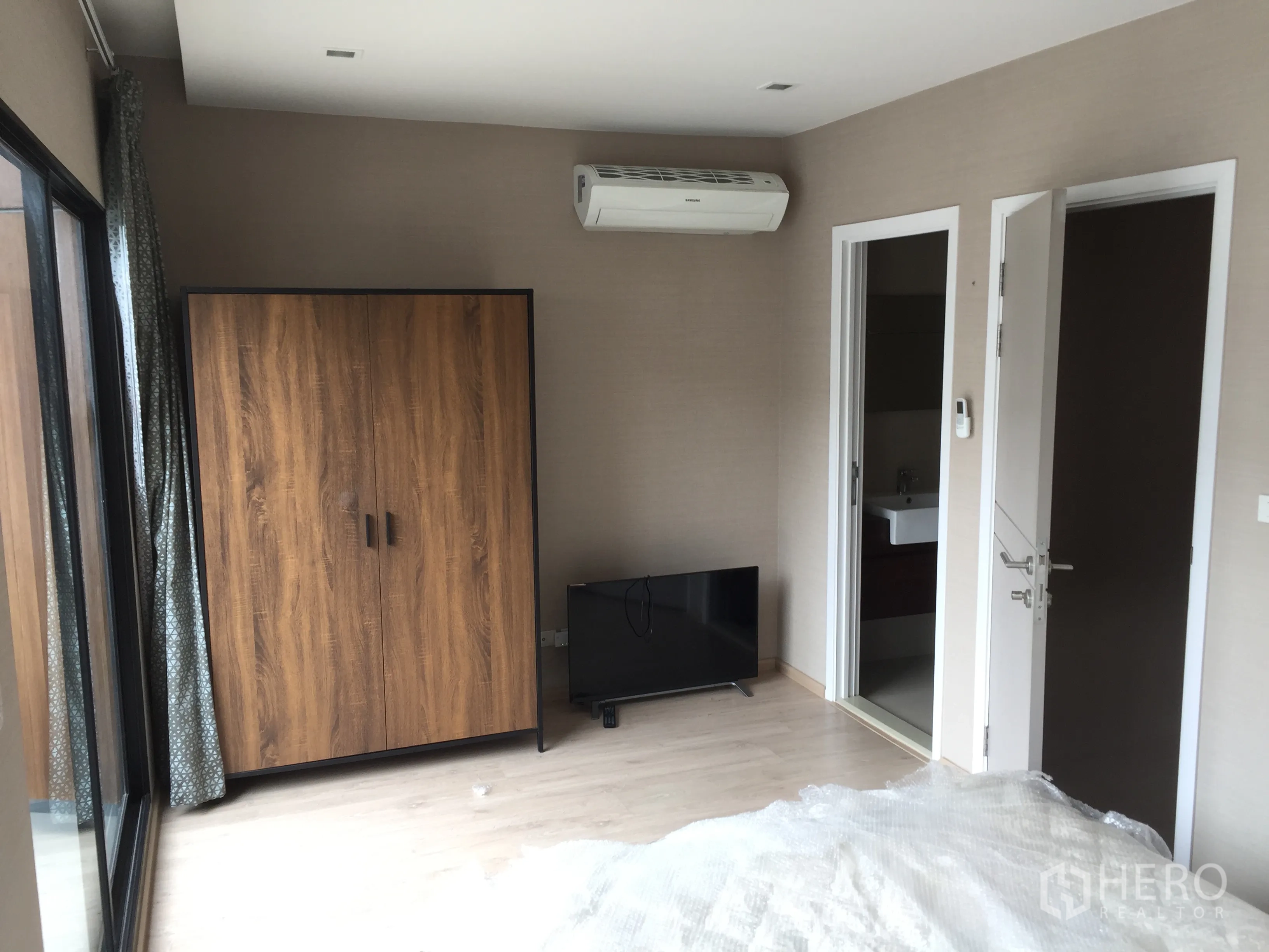 Townhouse for rent in Suan Luang, Bangkok - Bedroom with sliding door to balcony, wood wardrobe, air-conditioning and private bathroom entrance.
