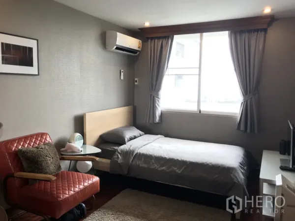 公寓 出租在Watthana, Bangkok - 次卧配单人床，大窗与灰色窗帘，配红色皮椅。