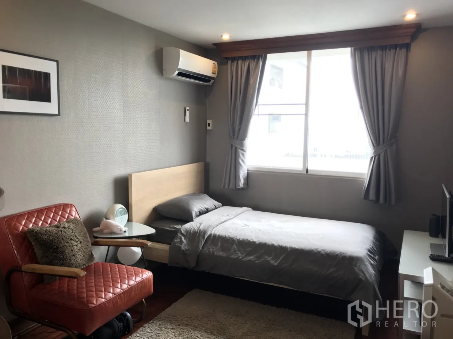 公寓 出租在Watthana, Bangkok - 次卧配单人床，大窗与灰色窗帘，配红色皮椅。