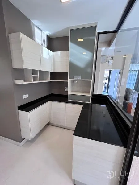 บ้าน ให้เช่าหรือขายในPrawet, Bangkok - มุมครัวรูปตัวแอล เคาน์เตอร์หินสีดำและตู้กระจก