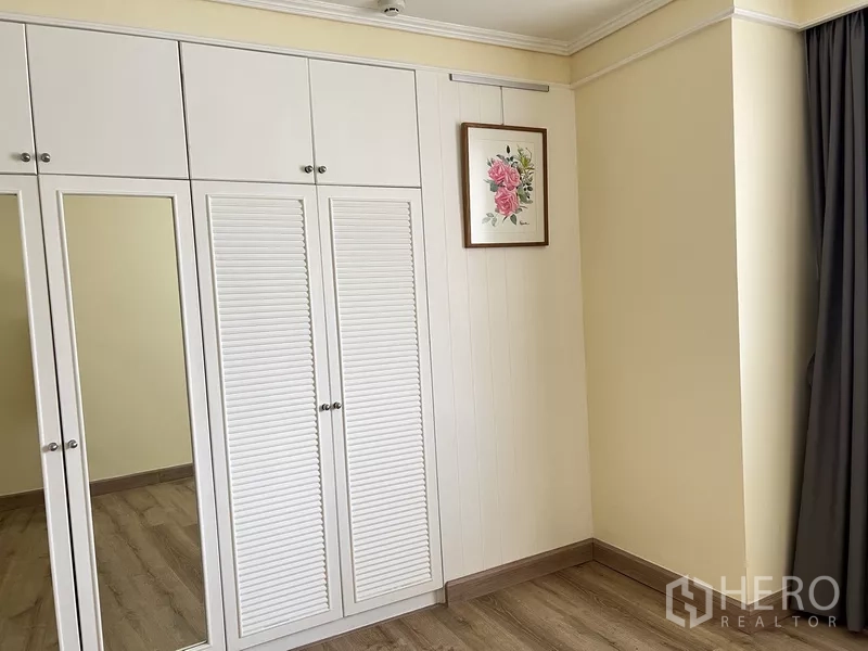 Condominium for rent in Khlong Toei, Bangkok - Additional built-in closets with louvered doors and mirrors in the bedroom.