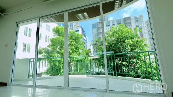 办公空间 出租 - 室内望向阳台的景色，落地推拉门、绿色栏杆与城市建筑。
