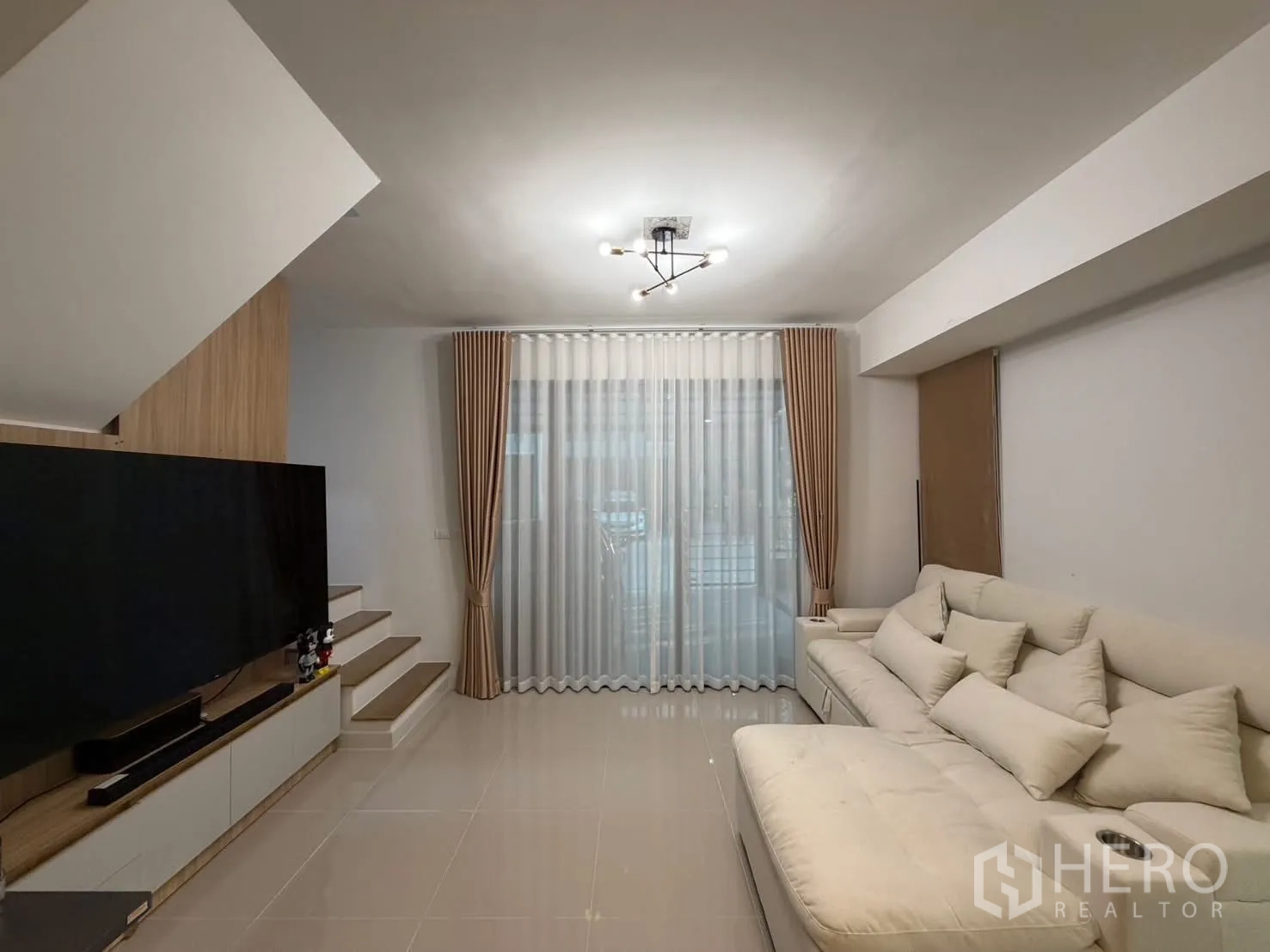联排别墅 for rent in Bang Phli, Samut Prakan - 客厅朝向楼梯与电视背景墙，配超大电视与纱帘。