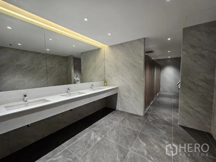 Office Space for rent in Bang Rak, Bangkok - Renovated restroom with long vanity, under-mount sinks, mirrors, and tiled floors and walls.