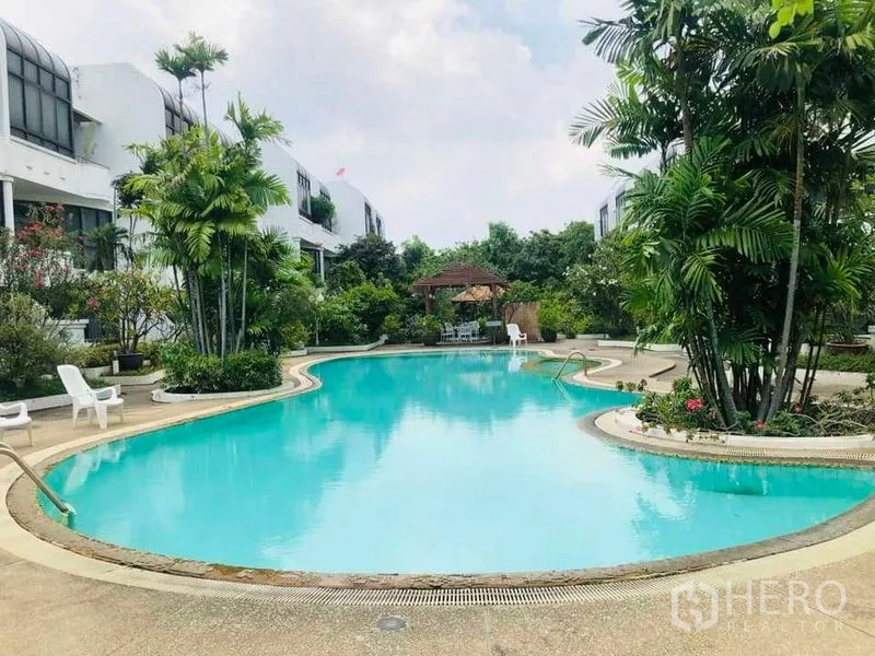 Townhouse for rent in Yan Nawa, Bangkok - Resort-style freeform swimming pool surrounded by palms, seating, and garden pavilions.
