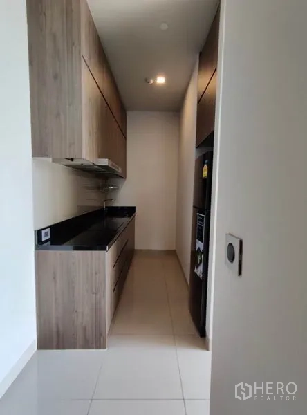 Condominium for rent in Watthana, Bangkok - Separate pantry or Thai kitchen in a galley layout with wood cabinets and black countertop.