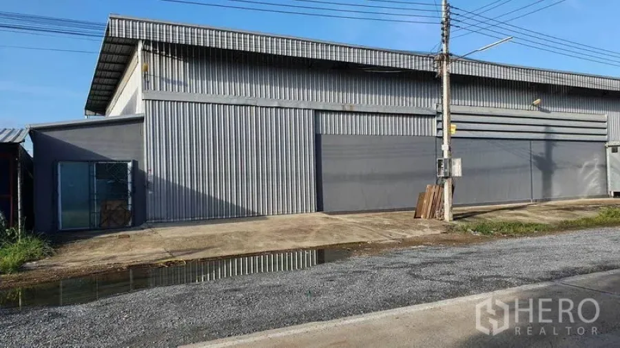 货栈 出租在Pathum Thani - 金属板外立面的仓库，配超宽推拉门与混凝土车道。