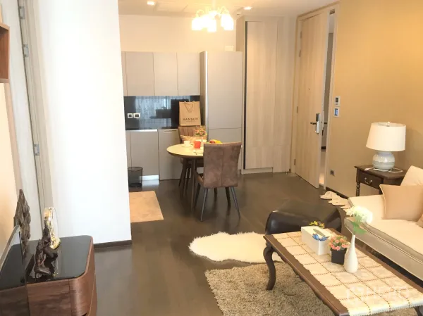 Condominium for rent in Watthana, Bangkok - Open-plan living with compact modern kitchenette, round dining table, and light wood cabinetry.
