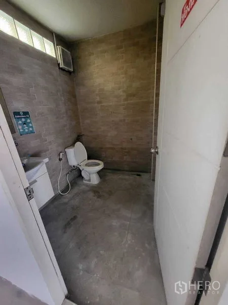 Shophouse for rent in Khlong Toei, Bangkok - Restroom inside the commercial unit featuring a toilet, sink, and tiled walls.