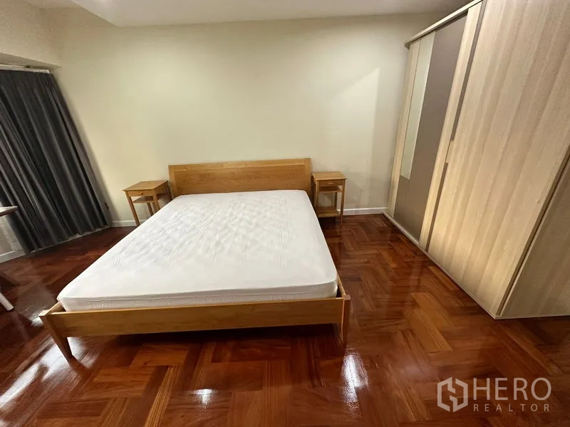 公寓 出租在Watthana, Bangkok - 第二卧室配木质床、床头柜与大衣柜，木地板光亮。