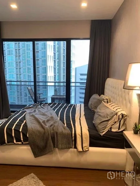 คอนโด ให้เช่าหรือขายในHuai Khwang, Bangkok - ห้องนอนใหญ่เตียงบุหนังและประตูระเบียง มองเห็นวิวเมือง
