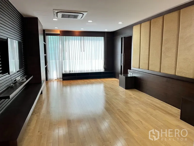 公寓 出租在Khlong Toei, Bangkok - 雅致起居空间，深色木饰面、电视柜与纱帘。