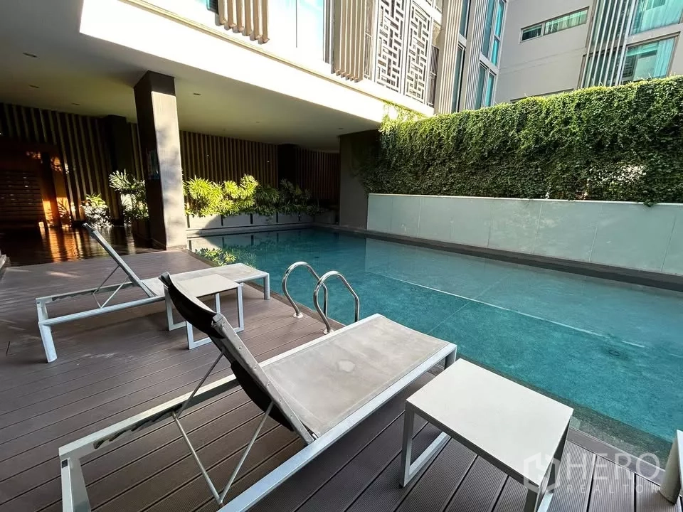 公寓 出租在Watthana, Bangkok - 公寓游泳池，旁设躺椅与绿化景观墙