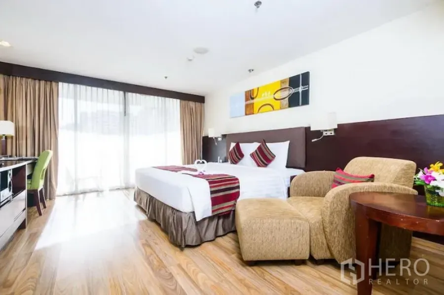 Condominium for rent in Khlong Toei, Bangkok - Spacious bedroom with king bed, seating area and floor-to-ceiling windows opening to the balcony.