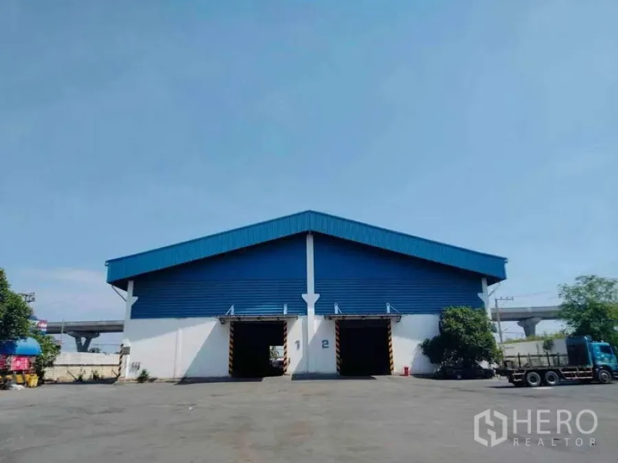 คลังสินค้า ให้เช่าหรือขายในBan Phaeo, Samut Sakhon - ด้านหน้าโกดังหลังคาสีน้ำเงิน มีช่องโหลดสินค้า 3 ช่องและลานรถบรรทุกกว้าง